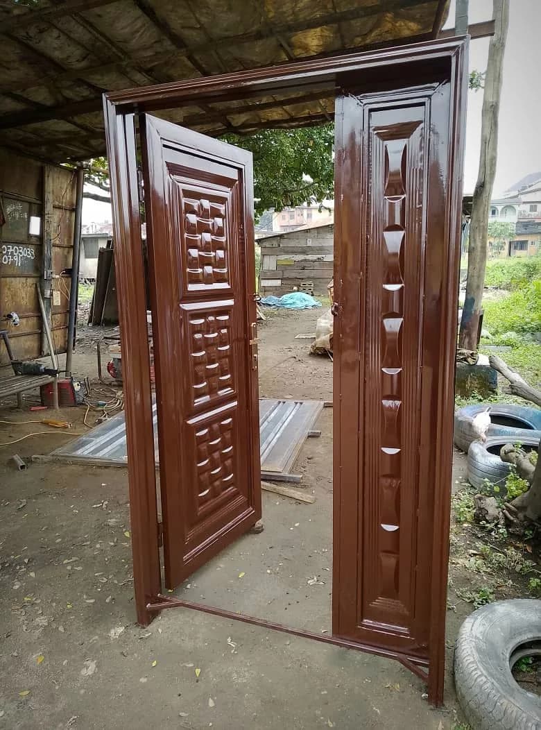Open double steel safety door with embossed panels, finished in glossy brown at the Loyal Point workshop in Ketu