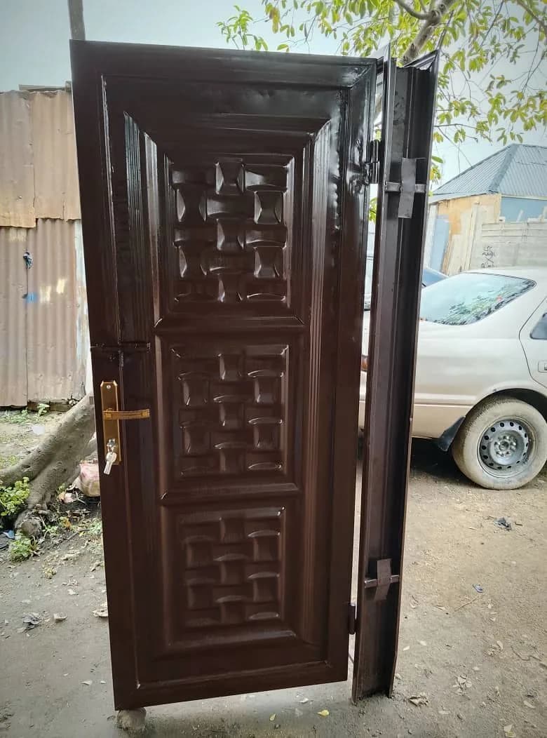 Dark brown steel safety door with embossed panels, gold handle and hinged frame, made by Loyal Point Construction